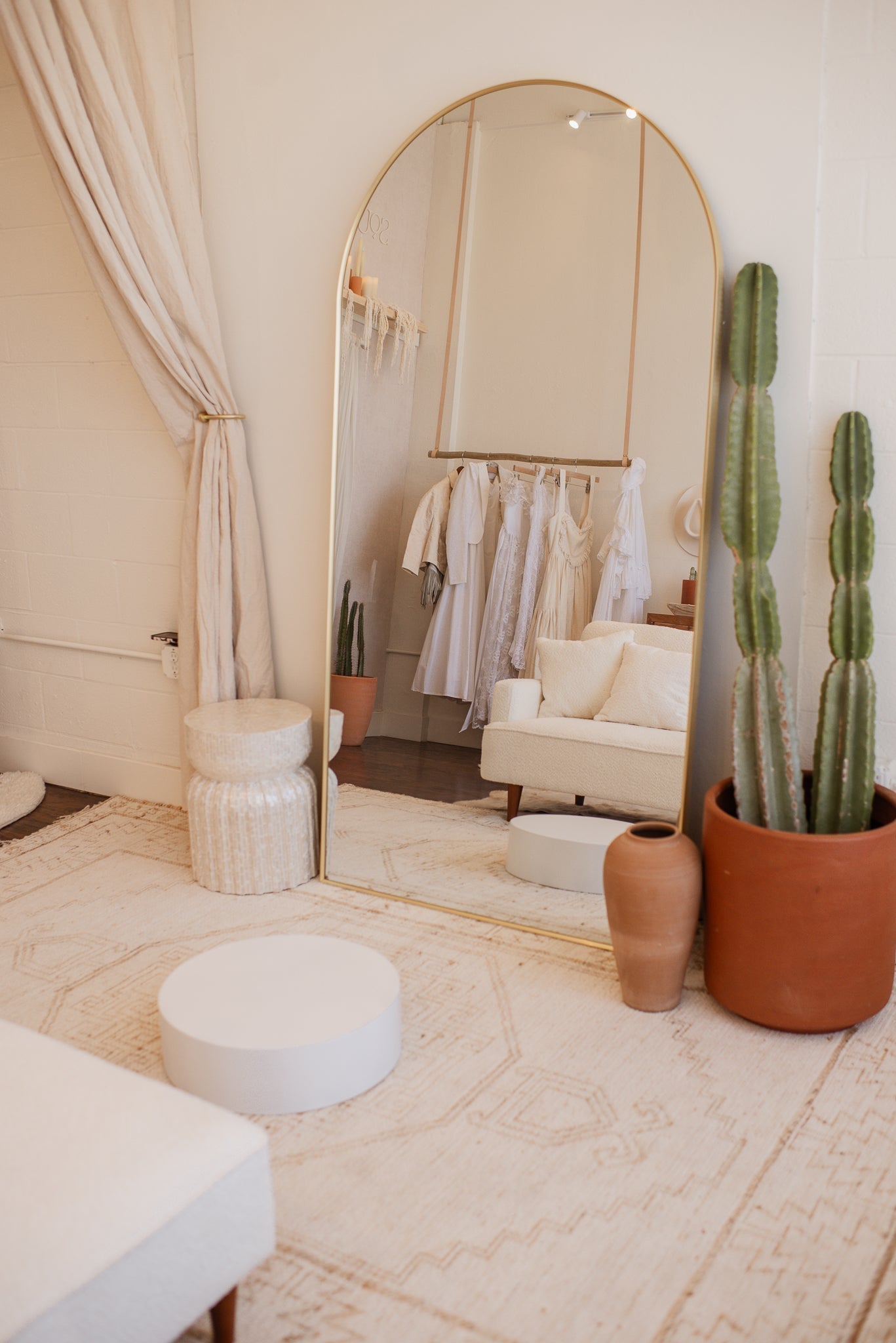 South of West Bridal showroom in Oceanside California with arched mirror reflecting vintage lace wedding dresses on rack and desert-inspired bridal boutique interior.
